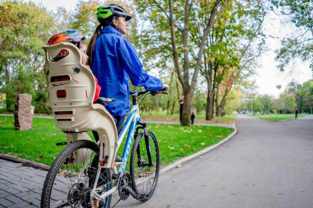 Woman and Child in Helmets Riding Bike in Park